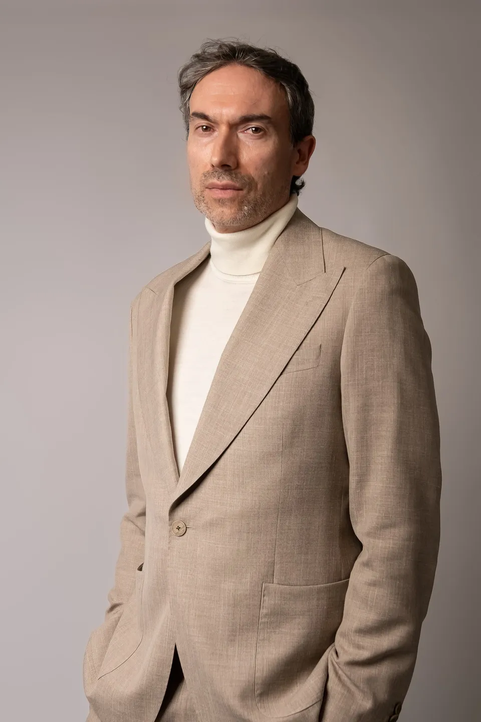 Kieron C, beige suit, white roll neck
