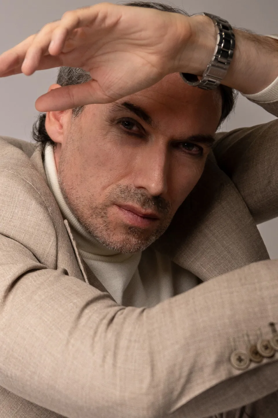 Kieron C, beige suit, hand over head